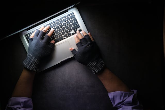 man in gloves typing on computer