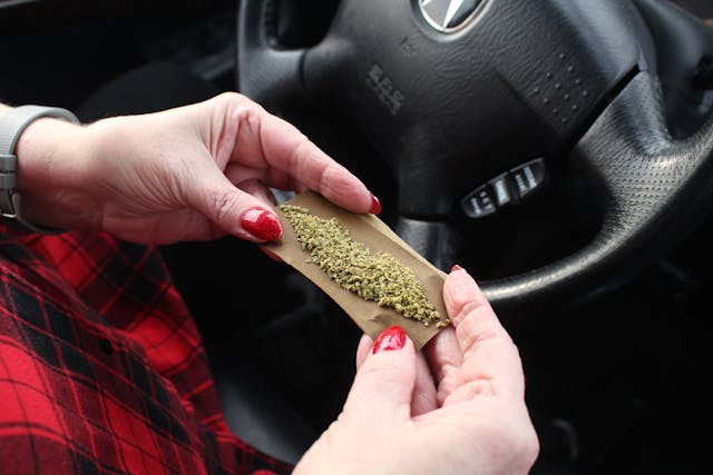 woman rolling marijuana joint in car